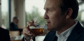 Movie still from “Another Round” (2020), directed by Thomas Vinterberg – A person holding a glass of beer; Close Up shot, Over the shoulder angle