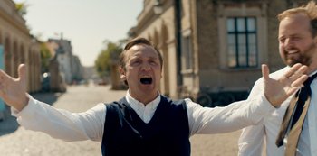 Movie still from “Another Round” (2020), directed by Thomas Vinterberg – A man with his mouth wide open standing on the street; Medium shot, Low angle