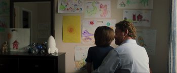 Movie still from “Greenland” (2020), directed by Ric Roman Waugh – A man and a child looking at drawings on a wall; Medium shot, Over the shoulder angle