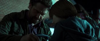 Movie still from “Greenland” (2020), directed by Ric Roman Waugh – A man and a child looking at a cell phone; Close Up shot, Over the shoulder angle