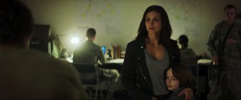 Movie still from “Greenland” (2020), directed by Ric Roman Waugh – A woman standing in front of a man in a room; Medium shot, Over the shoulder angle