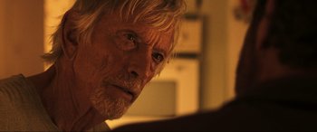 Movie still from “Greenland” (2020), directed by Ric Roman Waugh – An older man with long white hair looking at the camera; Close Up shot, Over the shoulder angle