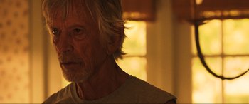 Movie still from “Greenland” (2020), directed by Ric Roman Waugh – An older man with long white hair looking at the camera; Close Up shot, Over the shoulder angle