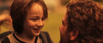 Movie still from “Greenland” (2020), directed by Ric Roman Waugh – A young girl and an older man smiling at each other; Close Up shot, Over the shoulder angle