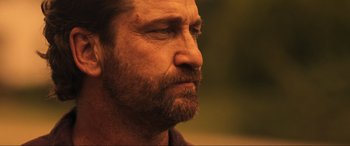 Movie still from “Greenland” (2020), directed by Ric Roman Waugh – A man with a beard looking to his left; Close Up shot, Over the shoulder angle