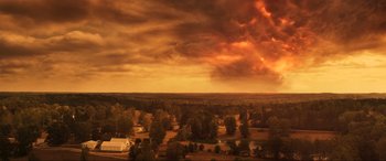 Movie still from “Greenland” (2020), directed by Ric Roman Waugh – An aerial view of a field with a sky filled with dark clouds; Extreme Wide shot, High angle