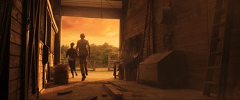 Movie still from “Greenland” (2020), directed by Ric Roman Waugh – Two people are walking in a barn at sunset; Wide shot, Low angle