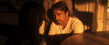 Movie still from “Greenland” (2020), directed by Ric Roman Waugh – A person sitting in a room; Medium shot, Over the shoulder angle