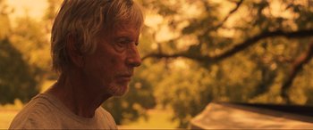 Movie still from “Greenland” (2020), directed by Ric Roman Waugh – An older man with white hair looking off into the distance; Close Up shot, Over the shoulder angle