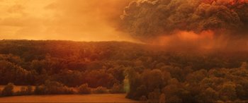 Movie still from “Greenland” (2020), directed by Ric Roman Waugh – A large cloud of smoke rises above a forest; Extreme Wide shot, High angle