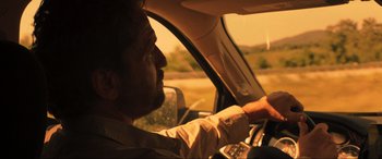 Movie still from “Greenland” (2020), directed by Ric Roman Waugh – A man sitting in the driver's seat of a car driving down a road; Close Up shot, Over the shoulder angle