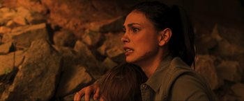 Movie still from “Greenland” (2020), directed by Ric Roman Waugh – A woman holding a baby in her arms in a cave; Close Up shot, High angle