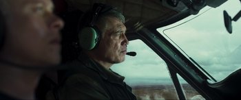 Movie still from “Greenland” (2020), directed by Ric Roman Waugh – An older man wearing headphones and a helicopter cockpit; Medium shot, Low angle