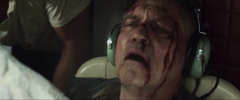 Movie still from “Greenland” (2020), directed by Ric Roman Waugh – A man with bandages on his face and ear muffs; Close Up shot, Low angle