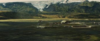 Movie still from “Greenland” (2020), directed by Ric Roman Waugh – An aerial view of an open field with mountains in the background; Extreme Wide shot, High angle