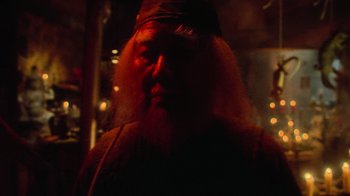 Movie still from “Gremlins” (1984), directed by Joe Dante – A man with long hair and a beard is in the dark; Close Up shot, Over the shoulder angle