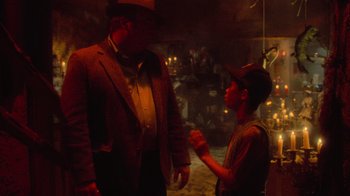 Movie still from “Gremlins” (1984), directed by Joe Dante – A man and a man in a suit and tie; Medium shot, Over the shoulder angle