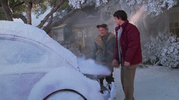 Movie still from “Gremlins” (1984), directed by Joe Dante – Two men standing next to a car covered in snow; Medium shot, High angle