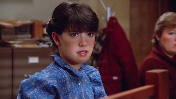 Movie still from “Gremlins” (1984), directed by Joe Dante – A young woman sitting in a chair wearing a blue dress; Close Up shot, Over the shoulder angle