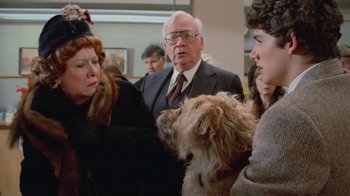 Movie still from “Gremlins” (1984), directed by Joe Dante – A group of people standing next to each other with a dog; Close Up shot, Over the shoulder angle