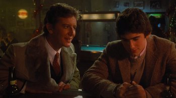 Movie still from “Gremlins” (1984), directed by Joe Dante – Two young men sitting at a table in front of a pool table; Medium shot, Over the shoulder angle