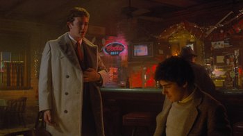 Movie still from “Gremlins” (1984), directed by Joe Dante – A man and a woman are standing in front of a bar; Medium shot, Over the shoulder angle