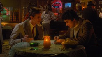 Movie still from “Gremlins” (1984), directed by Joe Dante – Two young men sitting at a table in front of a candle; Medium shot, Over the shoulder angle