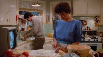 Movie still from “Gremlins” (1984), directed by Joe Dante – A woman and a man preparing food in a kitchen; Medium shot, Over the shoulder angle