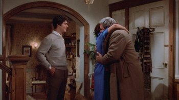 Movie still from “Gremlins” (1984), directed by Joe Dante – A group of people hugging in a living room; Medium shot, Over the shoulder angle