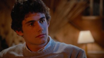 Movie still from “Gremlins” (1984), directed by Joe Dante – A young man in a white sweater looks to his left; Close Up shot, Low angle