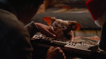 Movie still from “Gremlins” (1984), directed by Joe Dante – A person playing a keyboard with a stuffed animal; Close Up shot, Over the shoulder angle