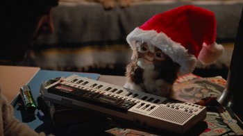 Movie still from “Gremlins” (1984), directed by Joe Dante – A cat sitting on top of a keyboard wearing a santa hat; Close Up shot, High angle