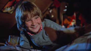Movie still from “Gremlins” (1984), directed by Joe Dante – A young boy smiling while holding a teddy bear; Close Up shot, Low angle
