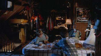 Movie still from “Gremlins” (1984), directed by Joe Dante – Two young boys sitting on top of a bed playing a game; Wide shot, High angle