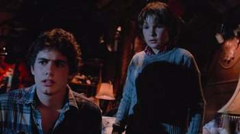 Movie still from “Gremlins” (1984), directed by Joe Dante – Two young boys standing next to each other in a dark room; Medium shot, Over the shoulder angle