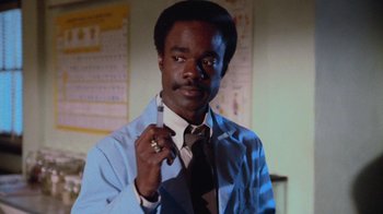 Movie still from “Gremlins” (1984), directed by Joe Dante – A man in a white lab coat holding a pen; Close Up shot, Low angle