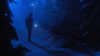 Movie still from “Gremlins” (1984), directed by Joe Dante – A person is standing in the dark with a flashlight; Extreme Wide shot, Low angle