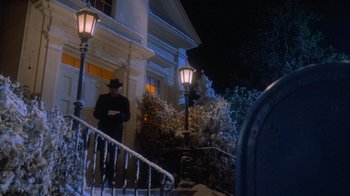 Movie still from “Gremlins” (1984), directed by Joe Dante – A man standing on the steps of a white house at night; Wide shot, Low angle