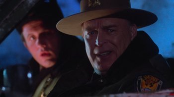 Movie still from “Gremlins” (1984), directed by Joe Dante – A man wearing a hat and a jacket; Close Up shot, Over the shoulder angle