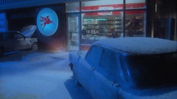 Movie still from “Gremlins” (1984), directed by Joe Dante – An old car parked in front of a store window; Wide shot, Over the shoulder angle