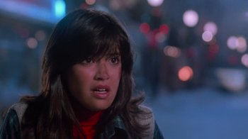 Movie still from “Gremlins” (1984), directed by Joe Dante – A young woman with long brown hair wearing a plaid shirt; Close Up shot, Over the shoulder angle