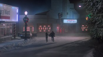 Movie still from “Gremlins” (1984), directed by Joe Dante – A couple of people standing on top of a snow covered ground; Extreme Wide shot, Low angle