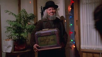 Movie still from “Gremlins” (1984), directed by Joe Dante – An old man holding a suitcase in a room with lights; Medium shot, Low angle