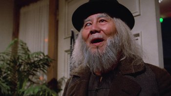 Movie still from “Gremlins” (1984), directed by Joe Dante – An old man with a long white beard wearing a black hat; Close Up shot, Low angle