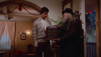 Movie still from “Gremlins” (1984), directed by Joe Dante – A man in a hat is handing a box to another man in a suit; Medium shot, Low angle