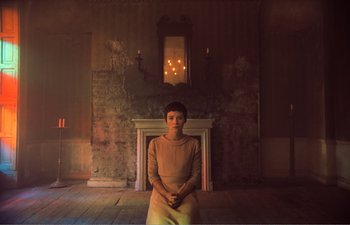 Movie still from “Gretel & Hansel” (2020), directed by Oz Perkins – A woman sitting in front of a fire place; Medium shot, Low angle