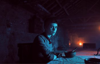 Movie still from “Gretel & Hansel” (2020), directed by Oz Perkins – A man sitting at a table in a dark room; Medium shot, Low angle