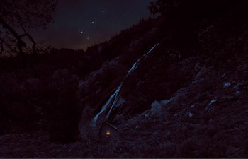 Movie still from “Gretel & Hansel” (2020), directed by Oz Perkins – A night time scene of a fire in the woods; Extreme Wide shot, High angle