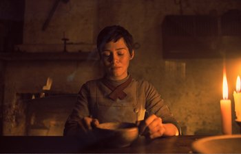 Movie still from “Gretel & Hansel” (2020), directed by Oz Perkins – A person sitting at a table with a plate in front of them; Medium shot, Low angle