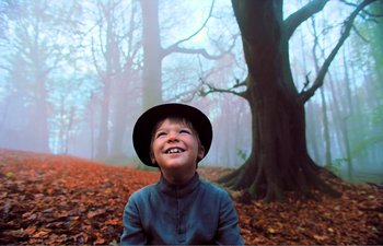Movie still from “Gretel & Hansel” (2020), directed by Oz Perkins – A young boy wearing a hat in the middle of a forest; Medium shot, Low angle